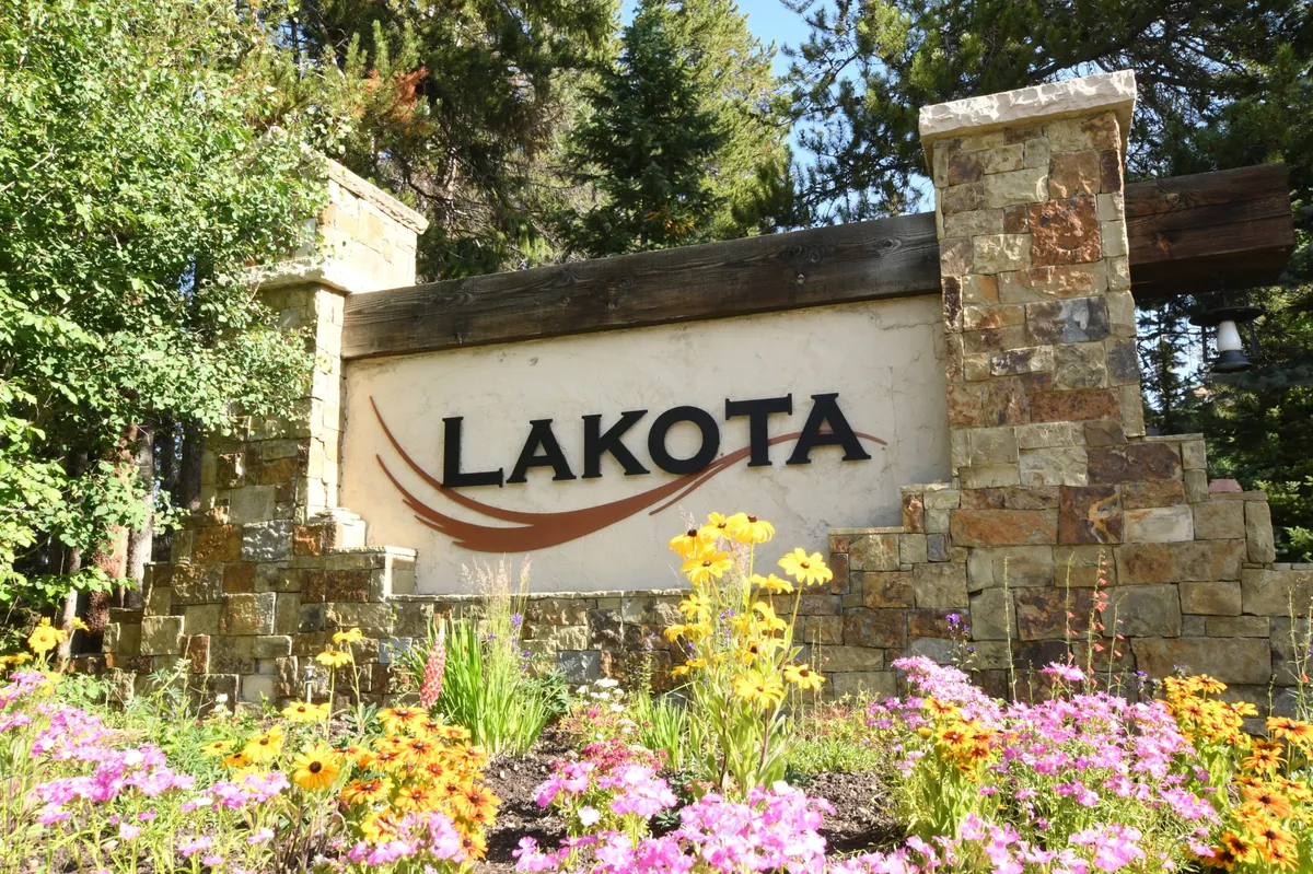 This image highlights the property's signage and curated landscaping at the entrance. The scene suggests an inviting arrival experience and hints at the opportunity for guests to explore and enjoy the natural setting and communal spaces around the home.