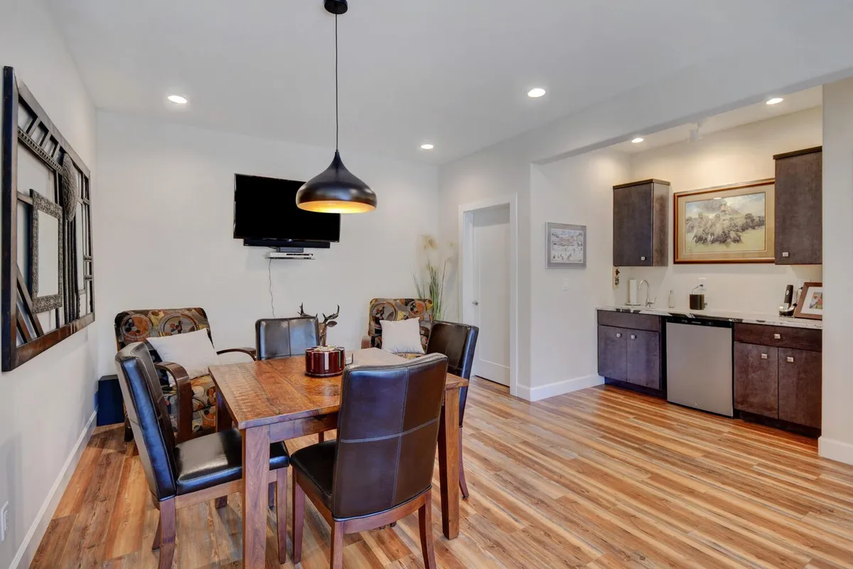 The image showcases a comfortable lower-level dining area with a wall-mounted smart TV and a compact kitchenette. The arrangement supports casual meals, watching games, and easy access to cooking facilities—an ideal self-contained retreat for extended stays or group gatherings.